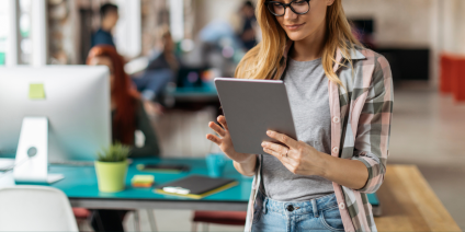 Kvinna tittar på en ipad i kontorsmiljö