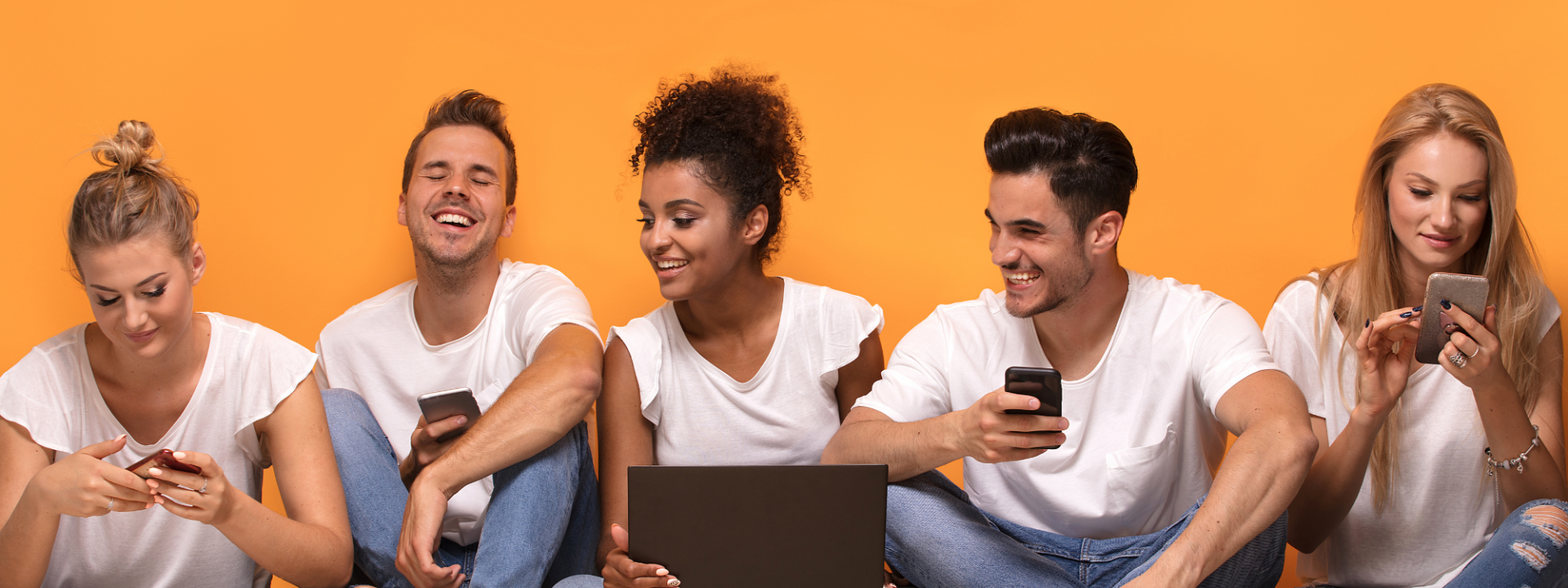 glada yngre personer tittar på mobilen och datorn