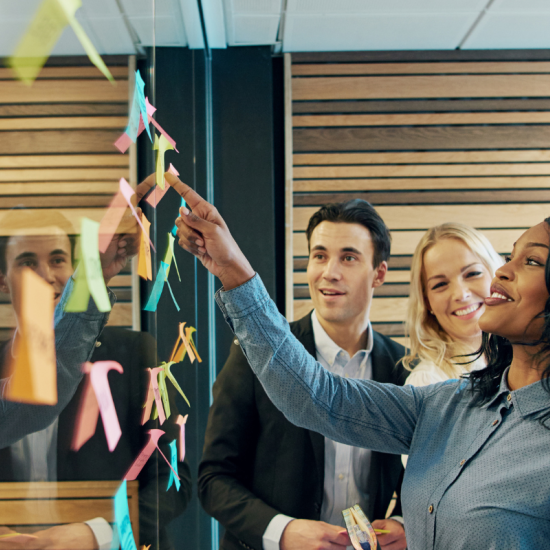 en grupp personer tittar på en tavla med post its